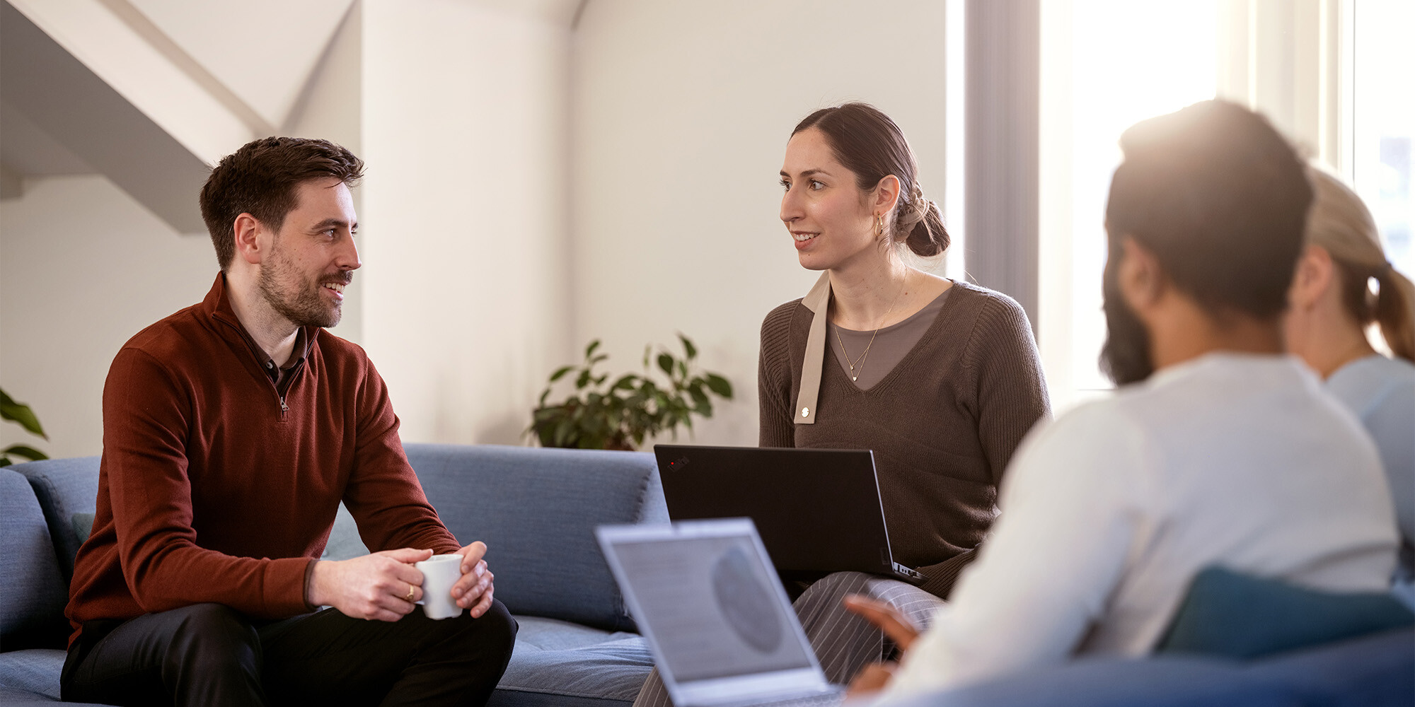 Flere kolleger hos Admincontrol sidder på en sofa og diskuterer sammen.