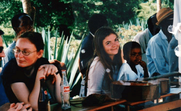 A group of people seated at a table, with a girl smiling at the camera beside a boy.