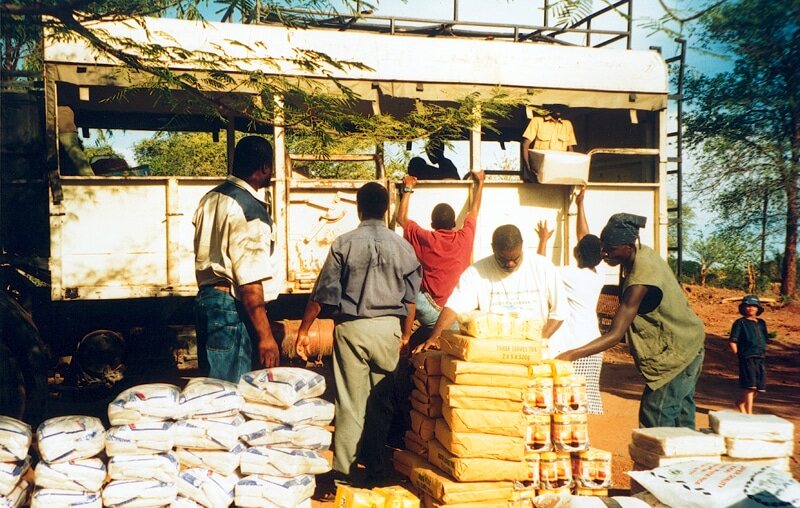  Several people are seen loading bags of rice onto a truck.