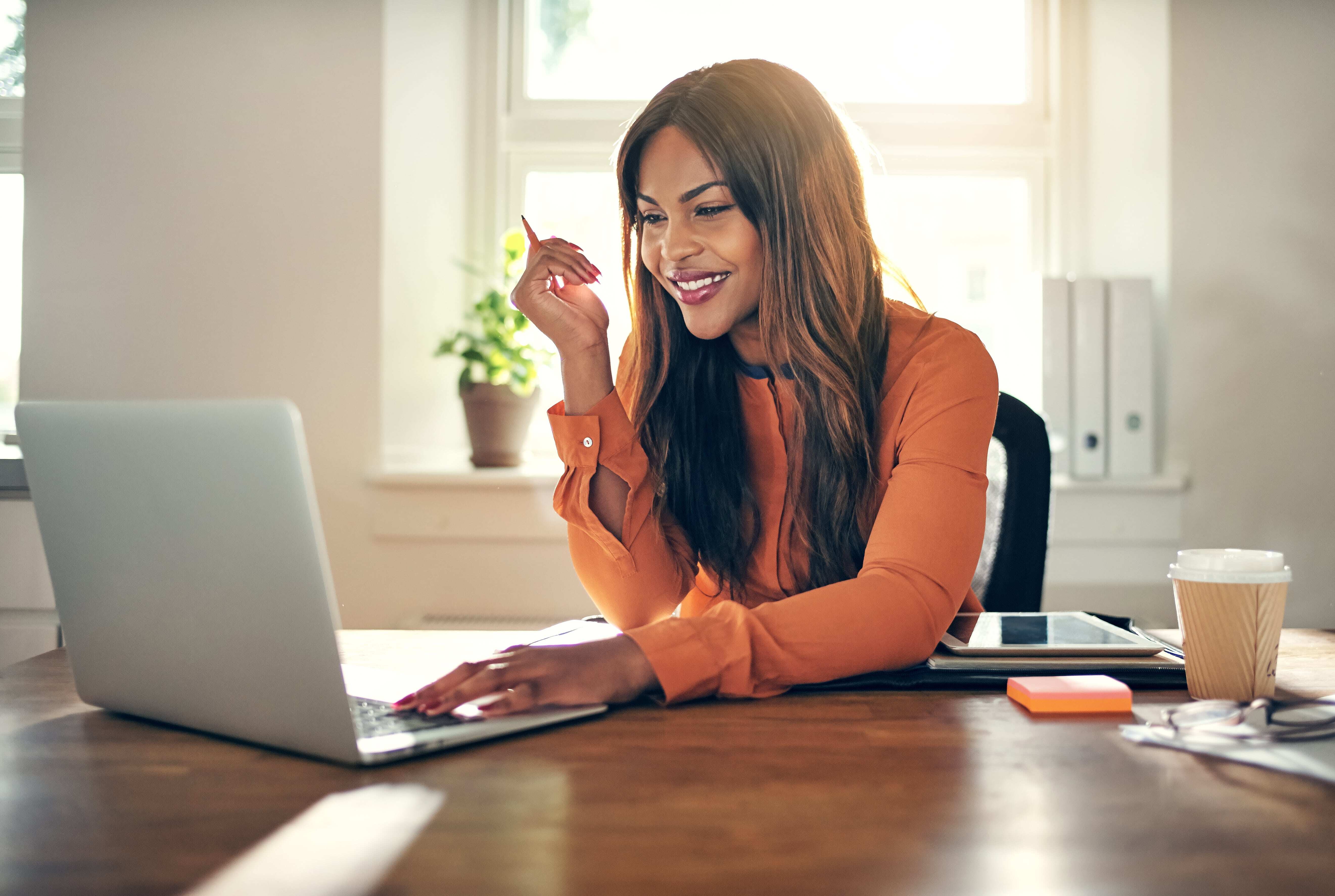 En smilende kvinde, der arbejder på sin laptop