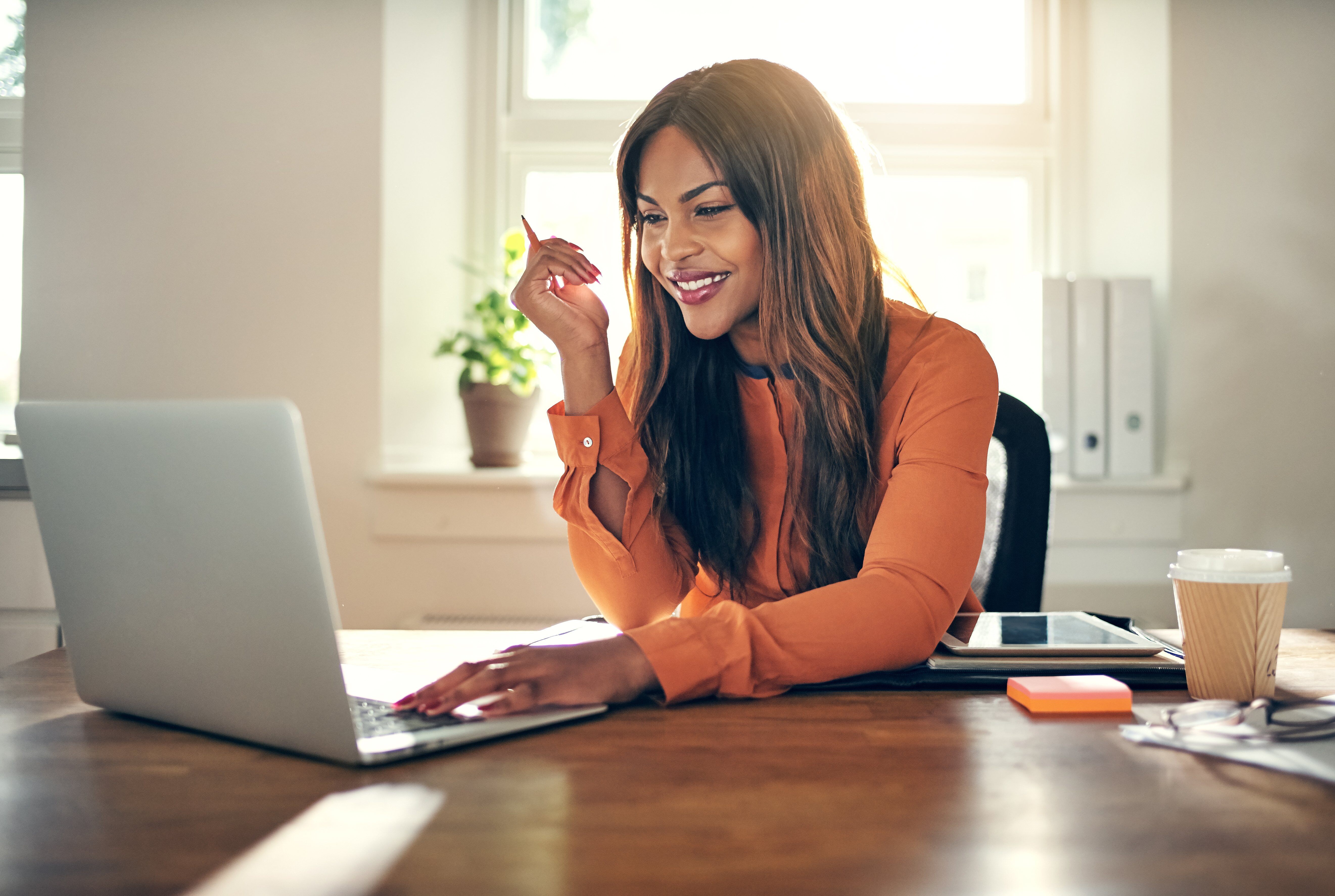 A woman smiling while working on her laptop.