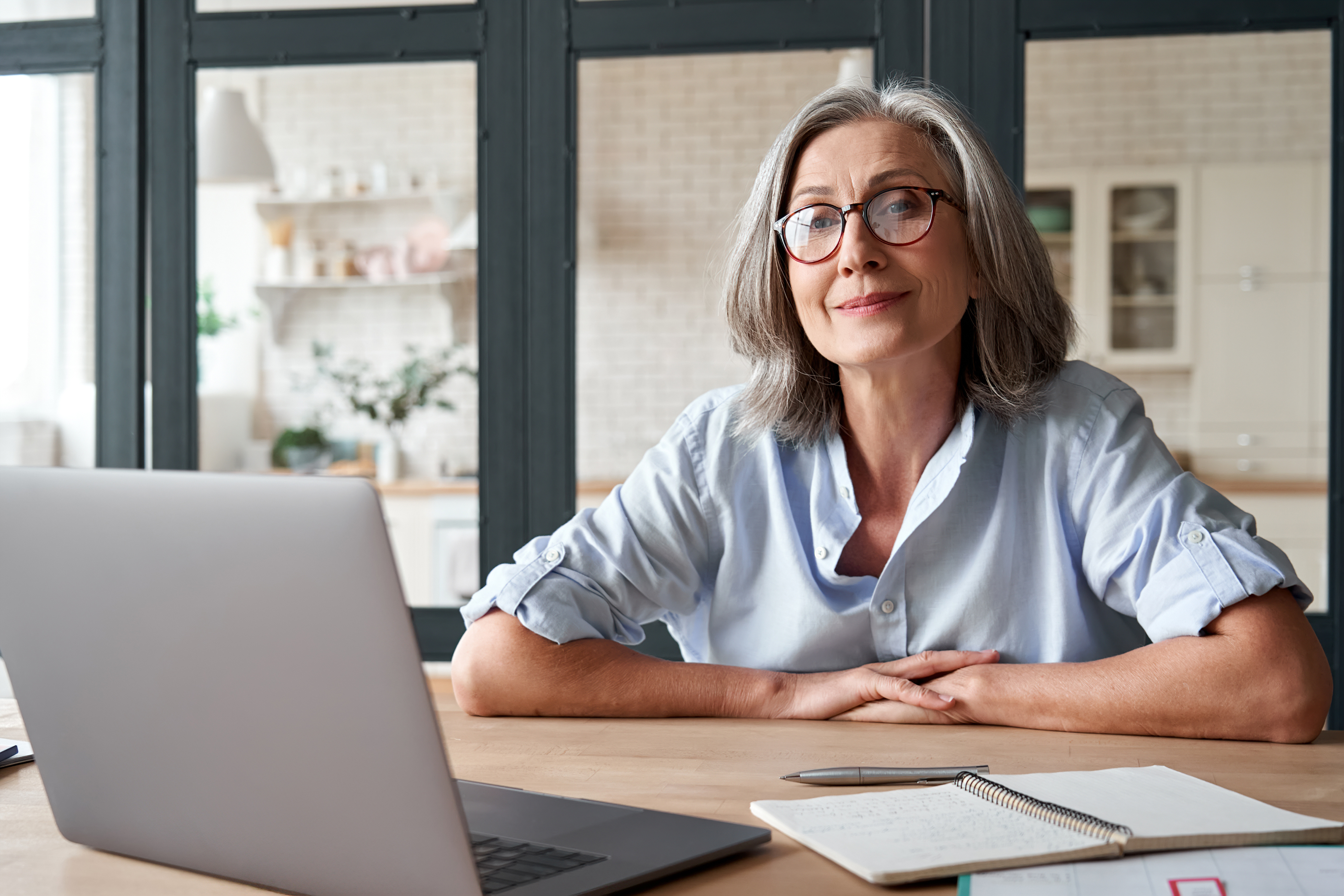 A woman with glasses is engaged in work at her desk.