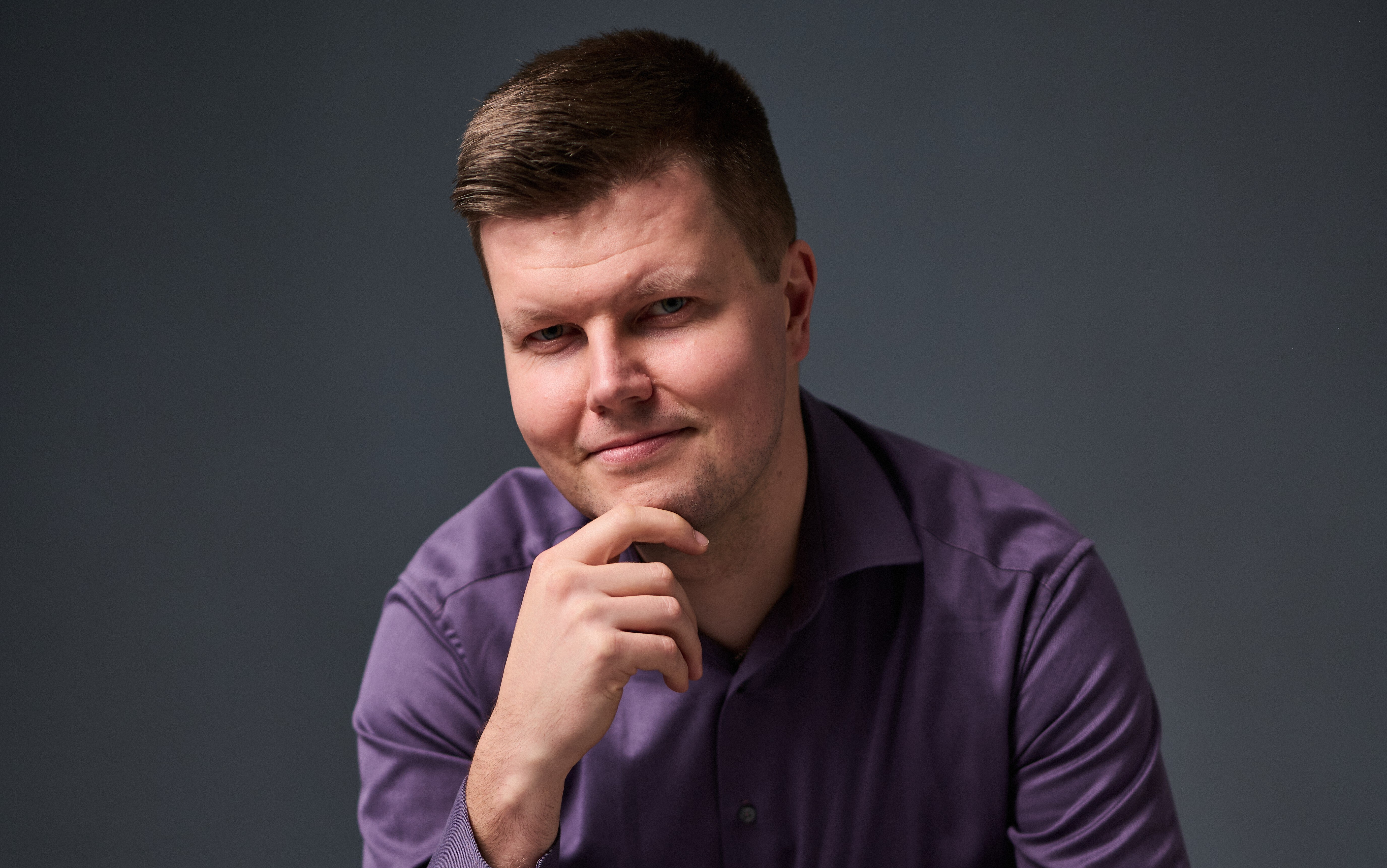 A smiling man with short brown hair looks into the camera