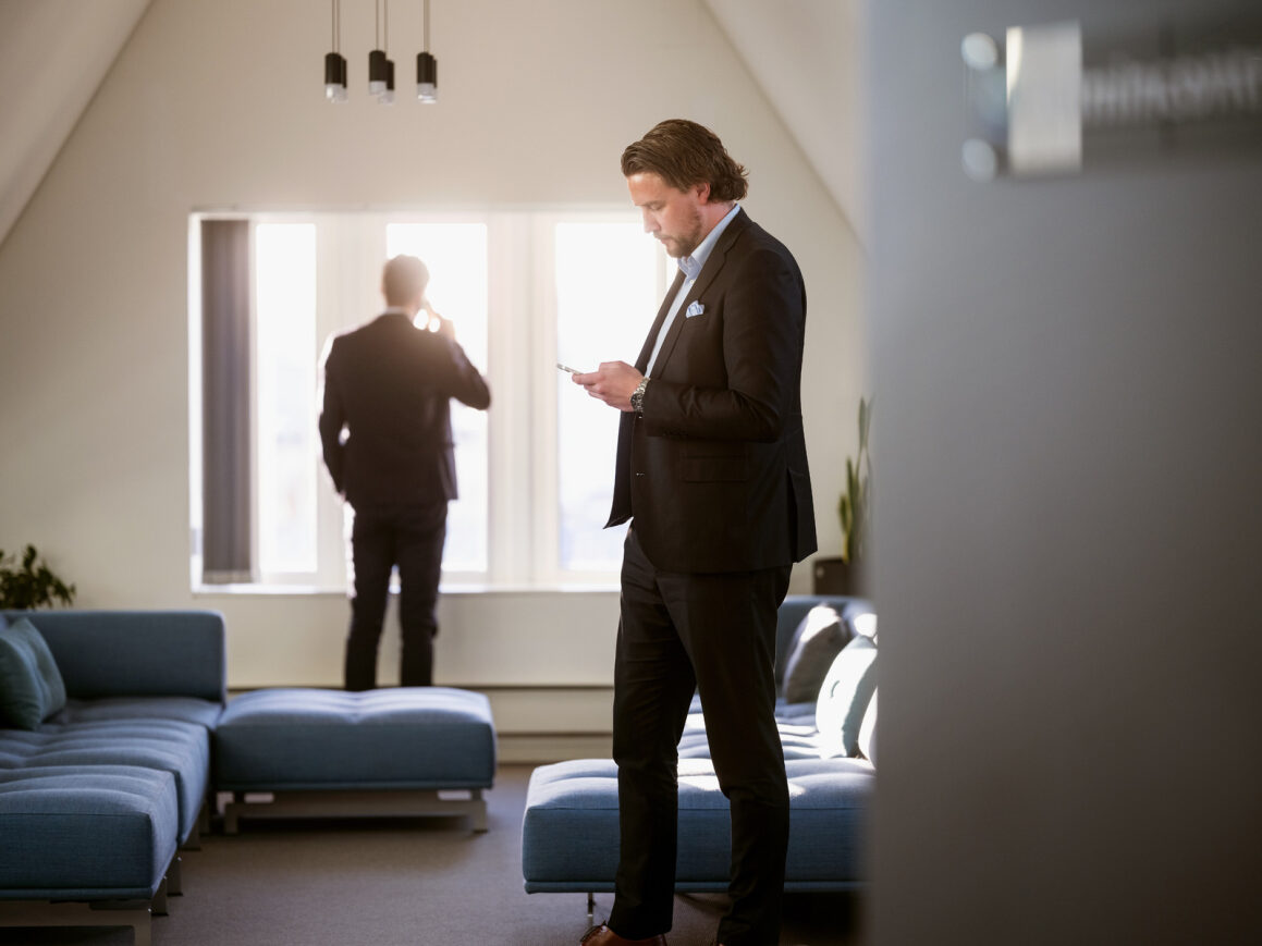 Two men in suits on phones making deals related to virutal data rooms